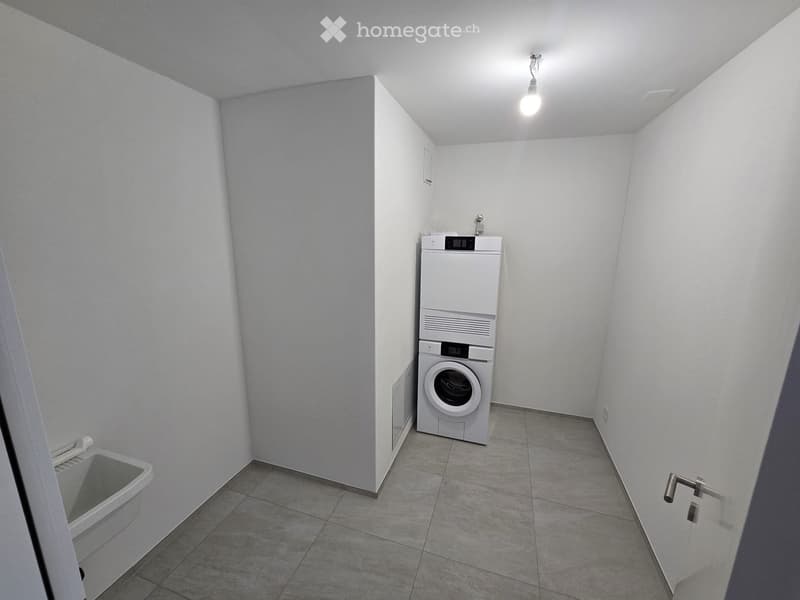Empty room with tiled floor, white walls, and a private washing machine in the corner.