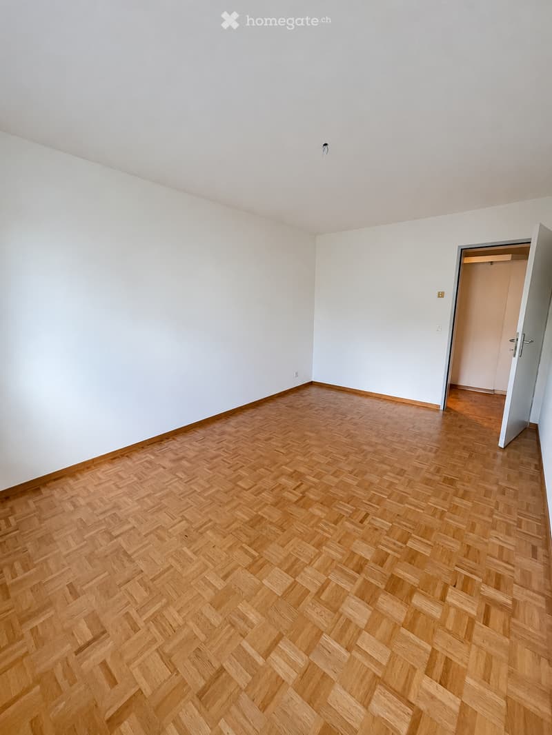 Empty room with light-colored walls and a herringbone-patterned wooden floor. No furniture or equipment is present.