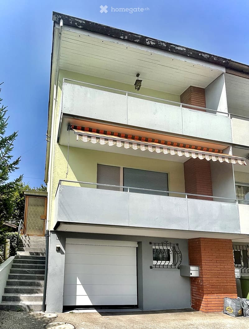 Two-story house with white and light green exterior, garage, balcony, and covered entrance with awning.