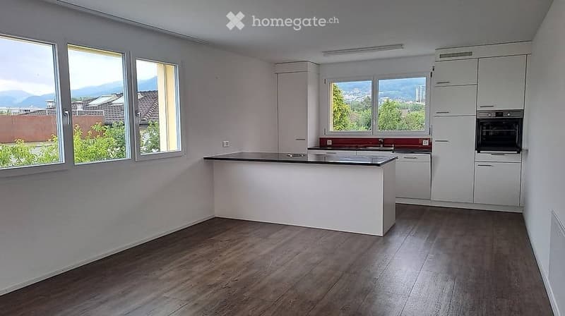 Modern kitchen with white cabinets, a central island, and large windows offering a scenic view.