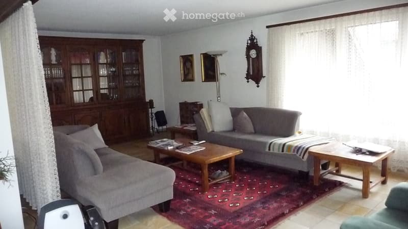 Living room with two sofas, coffee tables, a wooden cabinet, a clock on the wall, and a floor lamp.
