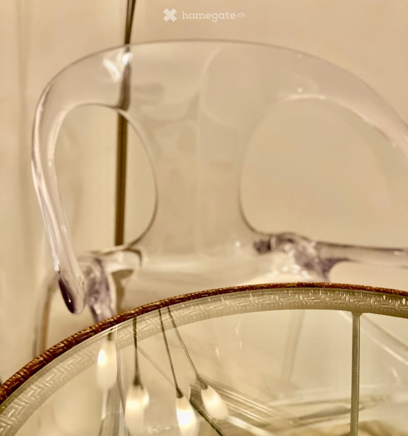 A modern, transparent glass table with a gold-trimmed edge and matching chairs, featuring sleek, contemporary design.