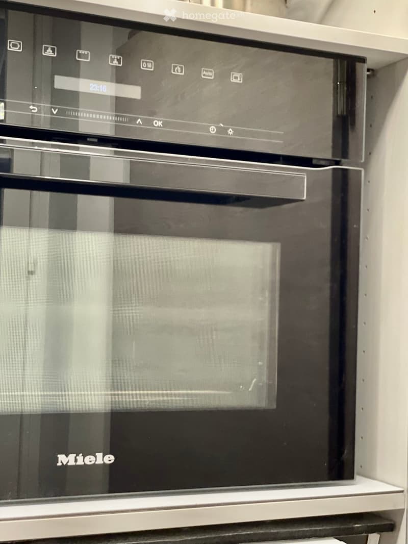 Modern built-in oven with digital display and control panel, featuring a sleek black design and stainless steel accents.