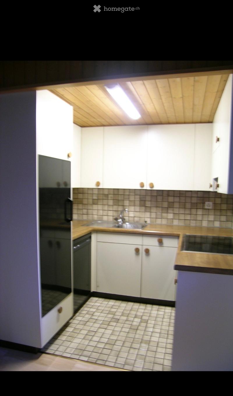 A small kitchen with white cabinets, a sink, and tiled flooring.