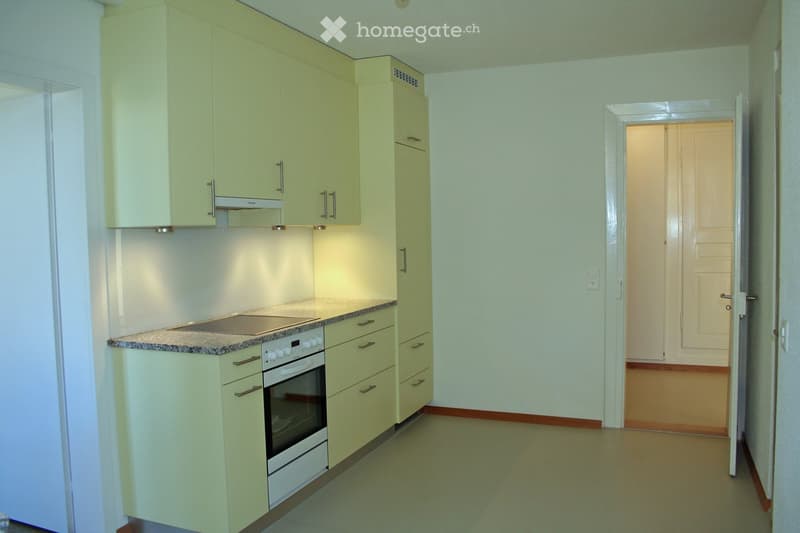 Modern kitchen with light green cabinets, stainless steel appliances, and granite countertop.