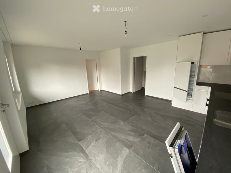 Empty room with white walls, dark grey tiled floor, and white cabinetry. No furniture or equipment present.