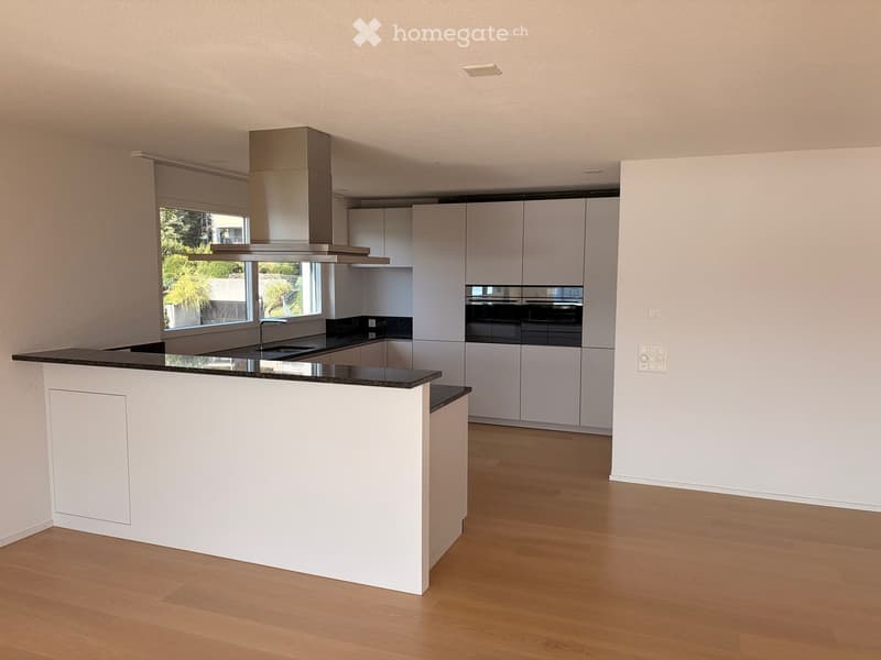 Modern kitchen with white cabinets, a central island, and stainless steel appliances including an oven and range hood.