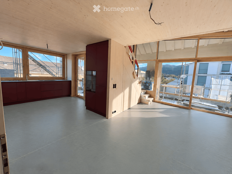 Empty room with wooden ceiling, large windows, and grey concrete floor. No furniture or equipment present.