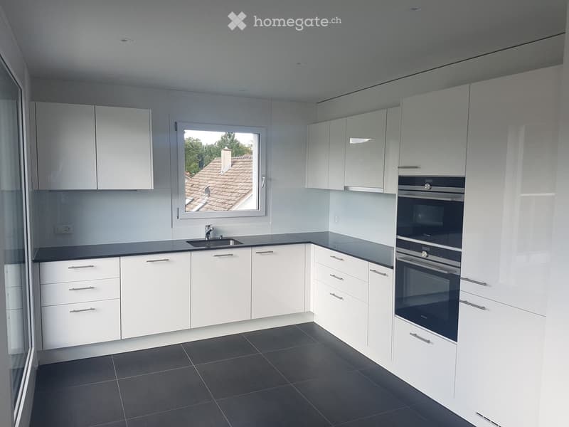 Modern kitchen with white cabinets, black countertops, and stainless steel appliances, including a sink and oven.