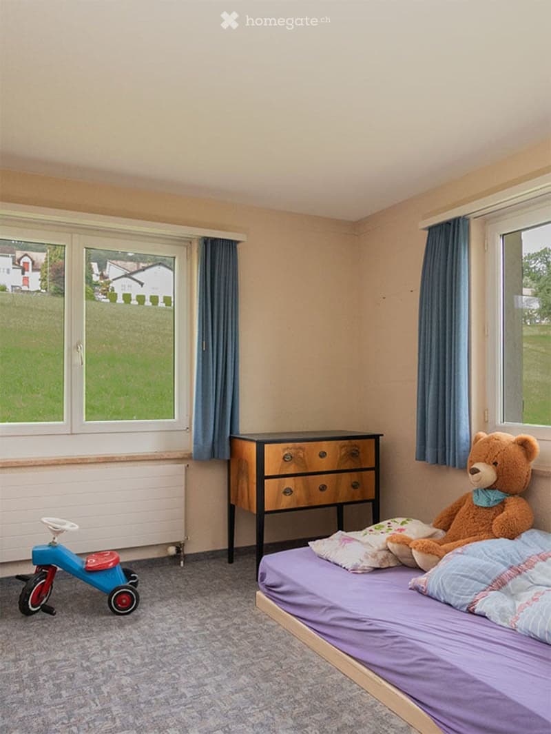 Child's bedroom with a single bed, pillows, a teddy bear, a dresser, and a toy tricycle near the window.
