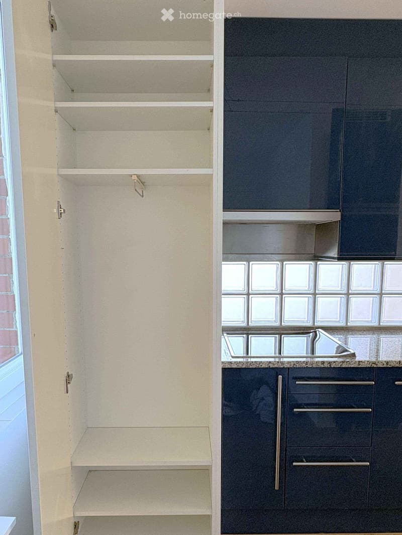 Modern kitchen with light-colored cabinets, dark lower cabinets, and a granite countertop. Features a built-in sink with a glass tile backsplash.