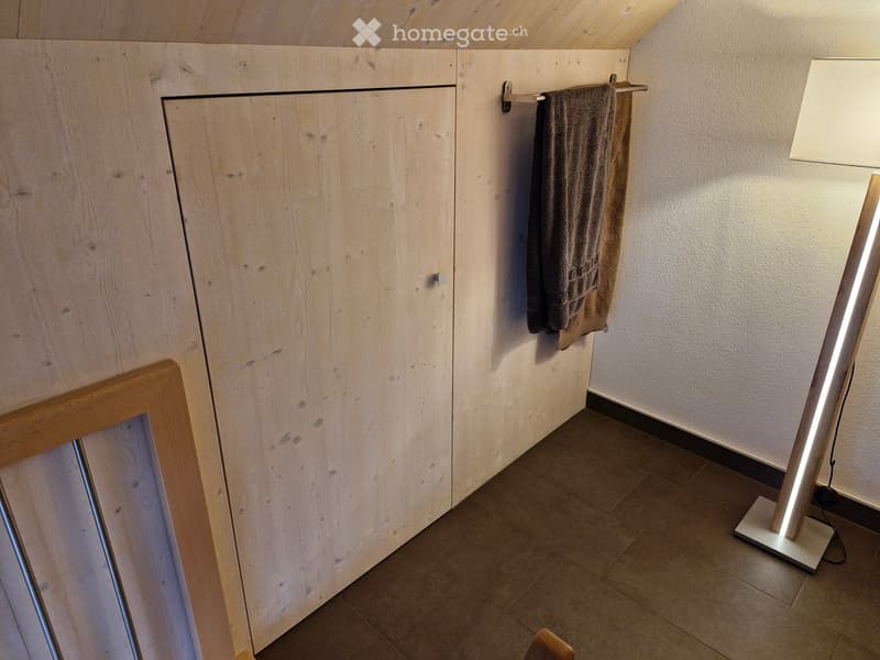 Empty room with wooden cabinet, towel rack, and floor lamp. No furniture or equipment present.