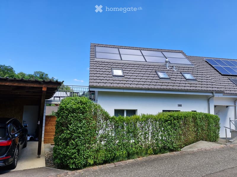 Two-story house with solar panels on the roof, a garage, and well-maintained hedges in the front yard.