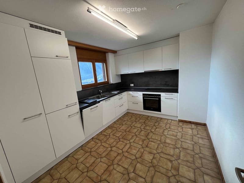 Modern kitchen with white cabinets, a black countertop, and a tiled floor. Features a sink, oven, and ample storage space.