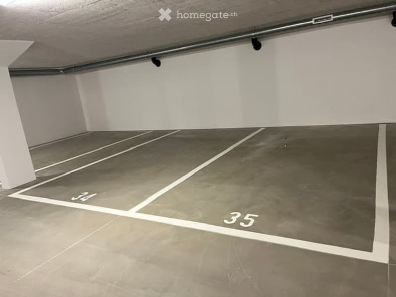 Underground parking space with numbered parking spots, white lines marking parking areas, and a concrete floor.