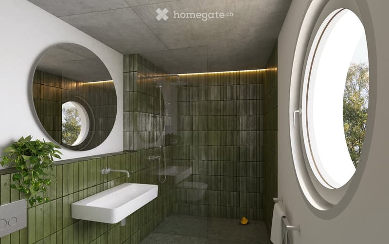 Modern bathroom with green tiled walls, a white sink, a large round mirror, a glass-enclosed shower, and a toilet. Features include built-in LED lighting and a small plant on the windowsill.