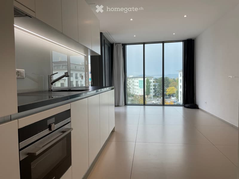 modern kitchen with white cabinets, tiled floor, sink, oven, large glass window with view