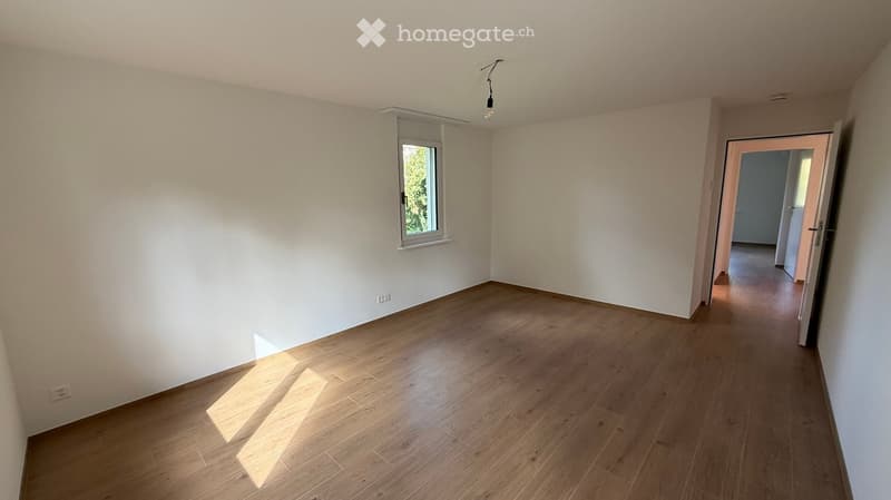 Empty room with wooden flooring, white walls, and a single window letting in natural light. No furniture or equipment is present.
