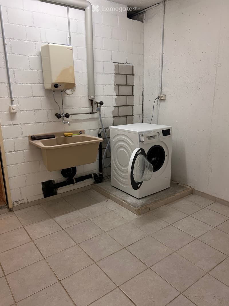 Utility bathroom with a washing machine, sink, and tiled floor.