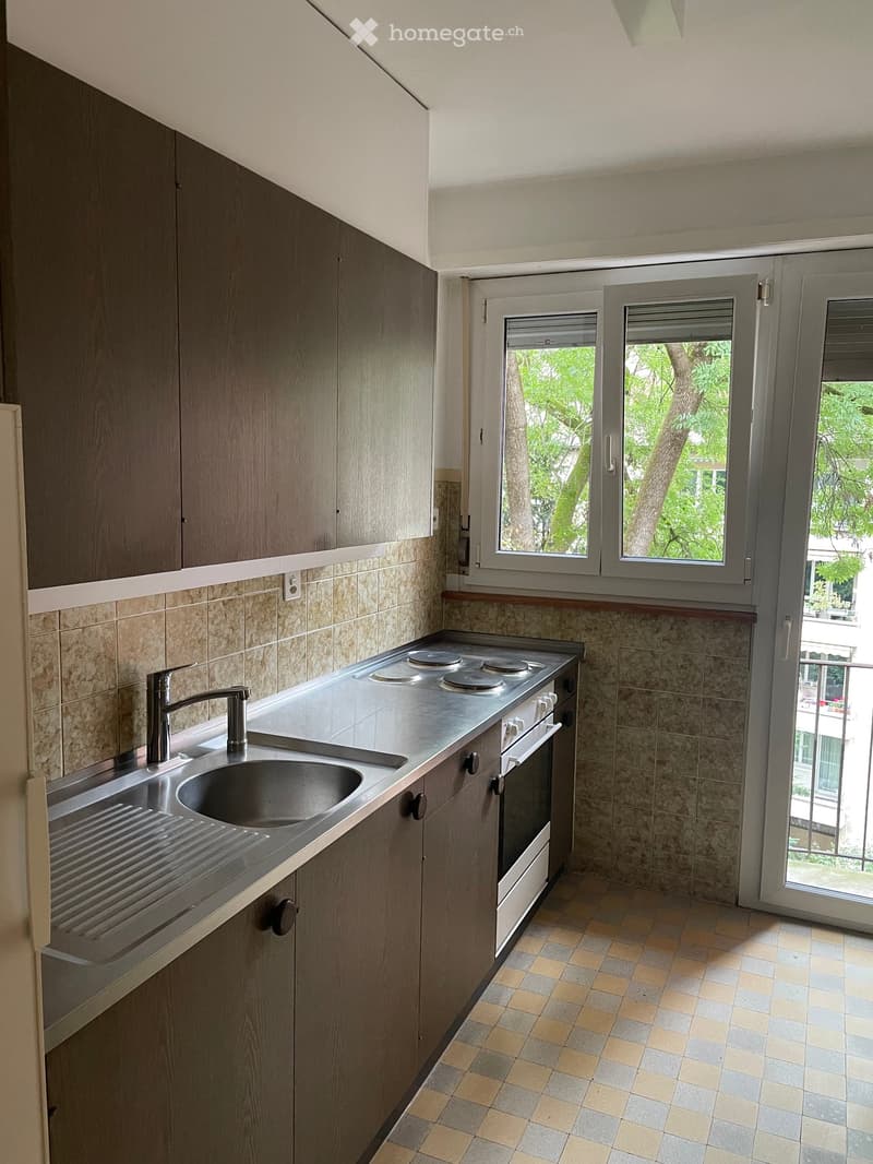 Modern kitchen with stainless steel sink, faucet, stove, and oven, surrounded by wooden cabinets and tiled walls.