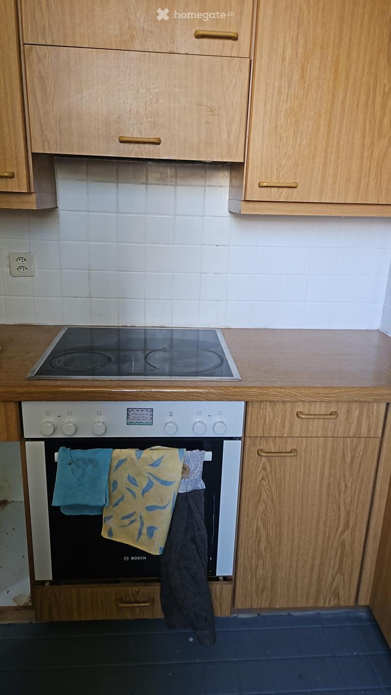 A kitchen with wooden cabinets, a stove, and an oven. Towels are hanging on the oven door.