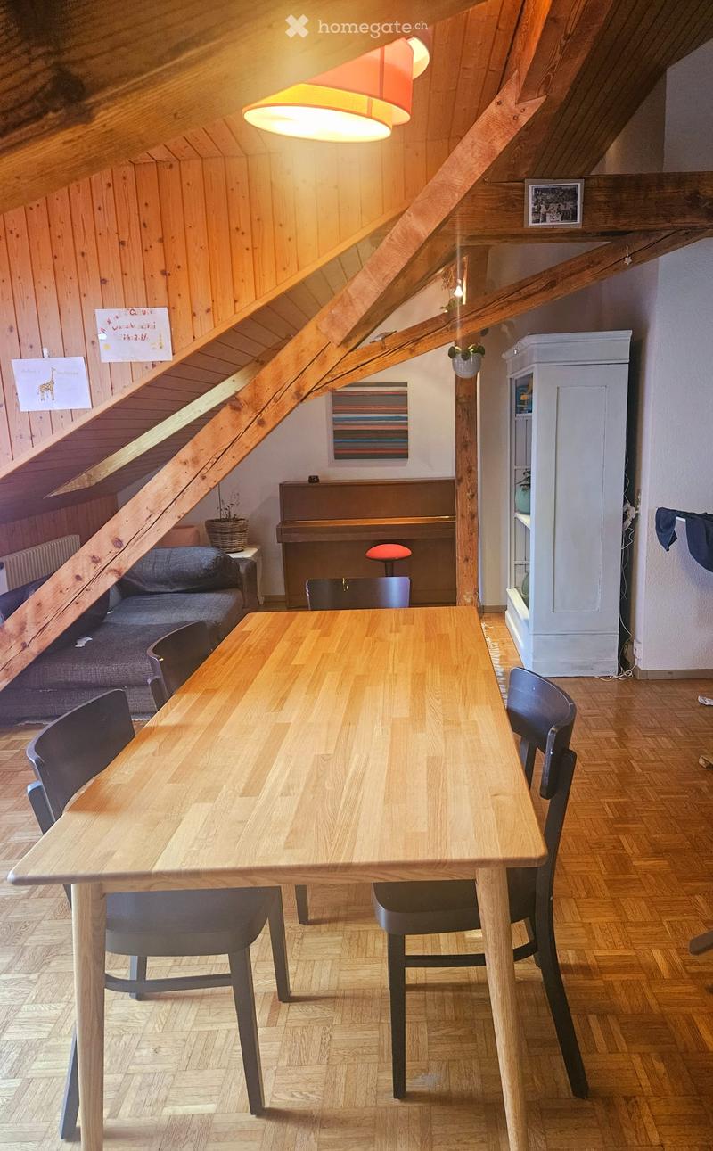 Dining area with wooden table and chairs, piano, cabinet, couch, and various decorative items.