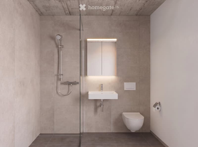 Modern bathroom with beige tiled walls and floor, white sink, toilet, and showerhead, illuminated mirror, and a toilet paper holder.