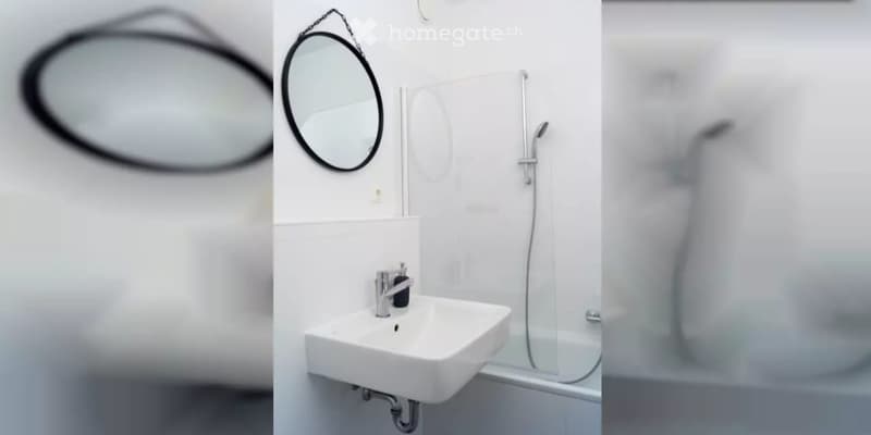 Modern bathroom with a white sink, round mirror, chrome faucet, and a glass-enclosed shower area.