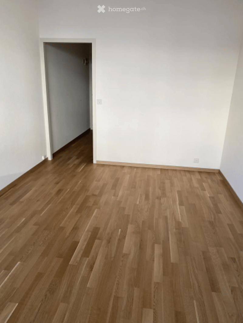 Completely empty room with bare white walls and wooden floor. No furniture or equipment.