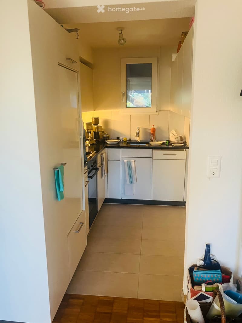 Modern kitchen with white cabinets, black countertops, and stainless steel appliances. Includes an oven, sink, coffee maker, and various kitchen items on the counter.