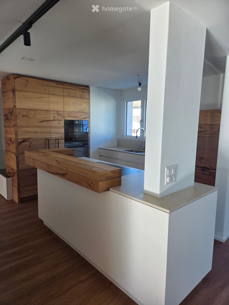 Modern kitchen with wooden cabinets, white countertops, and a central island with a wooden countertop.