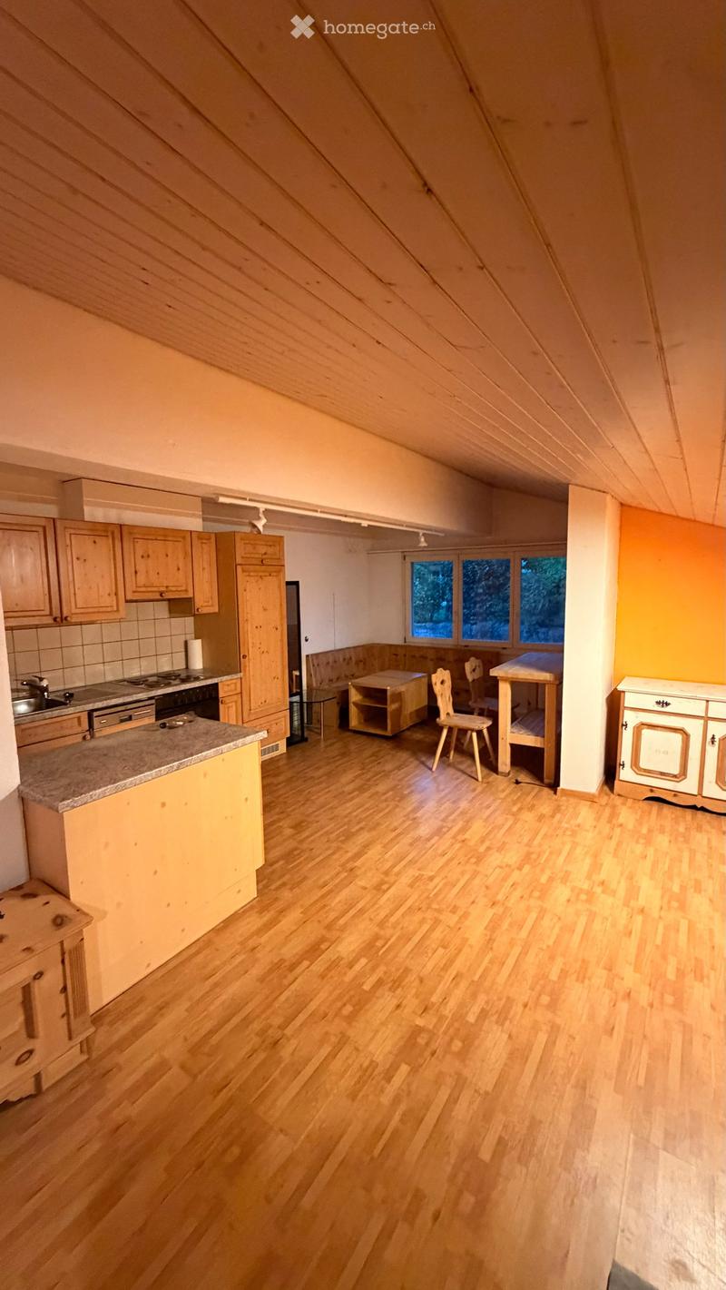 Bright, wooden-floored room with kitchen area featuring cabinets, sink, stove, and refrigerator, plus a dining area with a table and chairs.