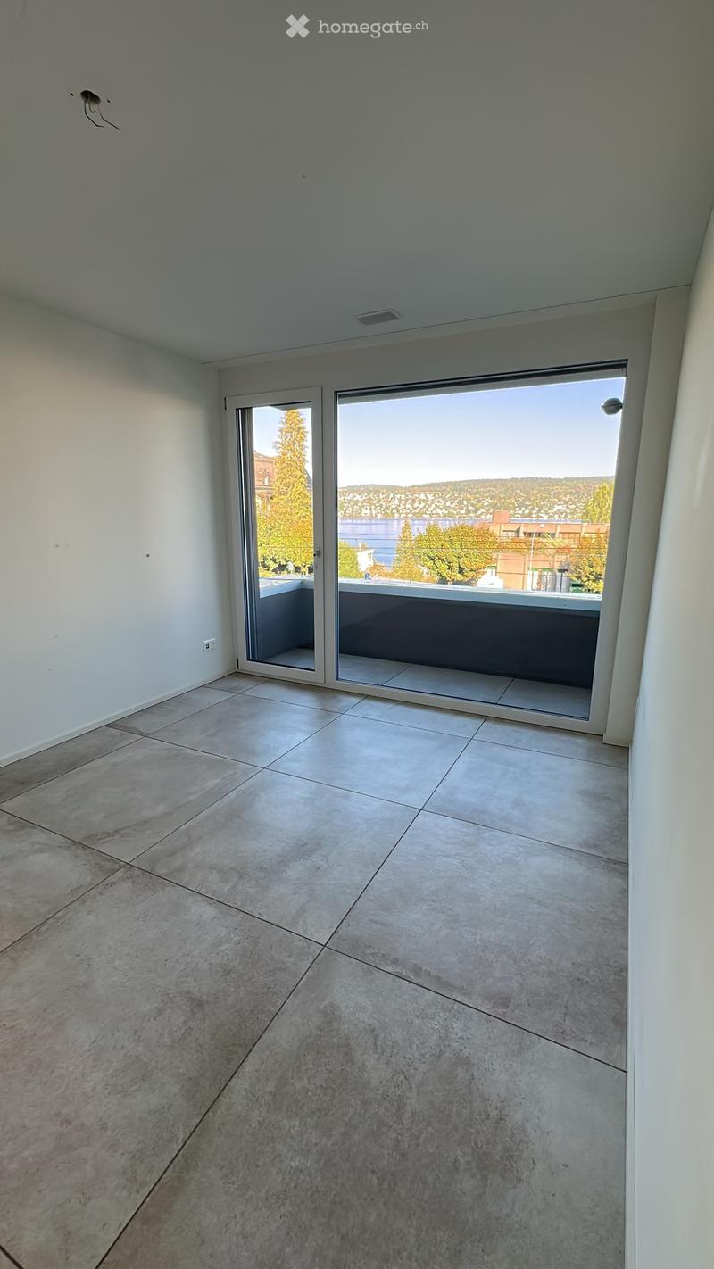 Empty room with tiled floor and large sliding glass doors leading to a balcony with a scenic view.