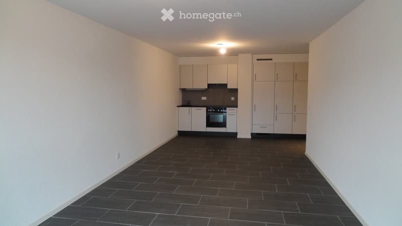 Modern kitchen with white cabinets, black tiled floor, and built-in oven.