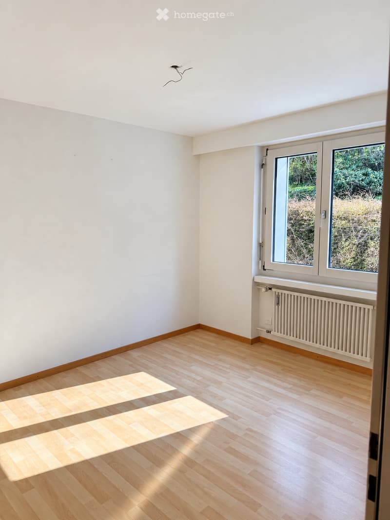 Empty room with light wooden flooring, white walls, and large windows letting in natural light. No furniture or equipment present.