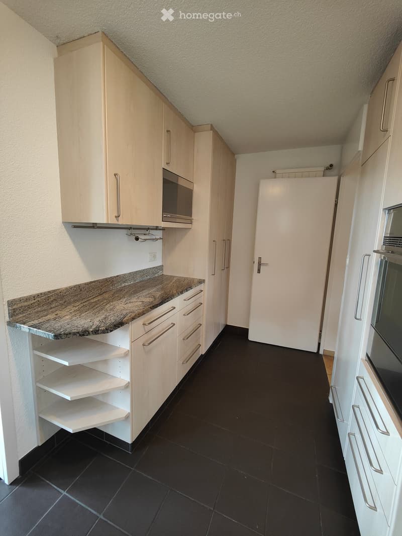 Modern kitchen with white cabinets, granite countertop, black tiled floor, and built-in microwave and oven.