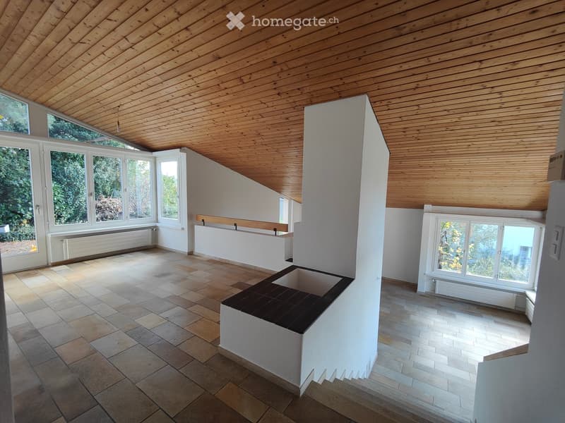 Bright, open room with wooden ceiling, large windows, tiled floor, and built-in bench seating area.