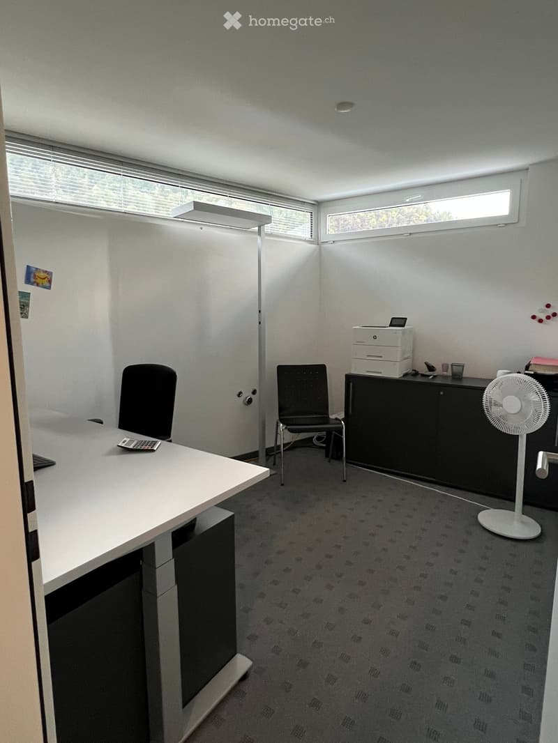 Office space with a white desk, two black chairs, a printer on a cabinet, a standing fan, and a calculator on the desk.