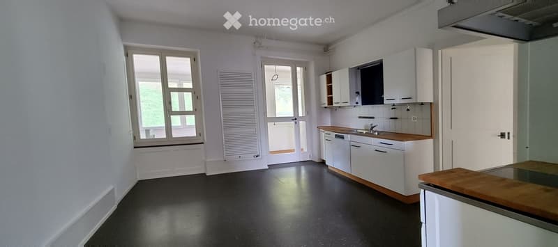 Modern kitchen with white cabinets, wooden countertops, and black flooring. Features a sink, faucet, and dishwasher.