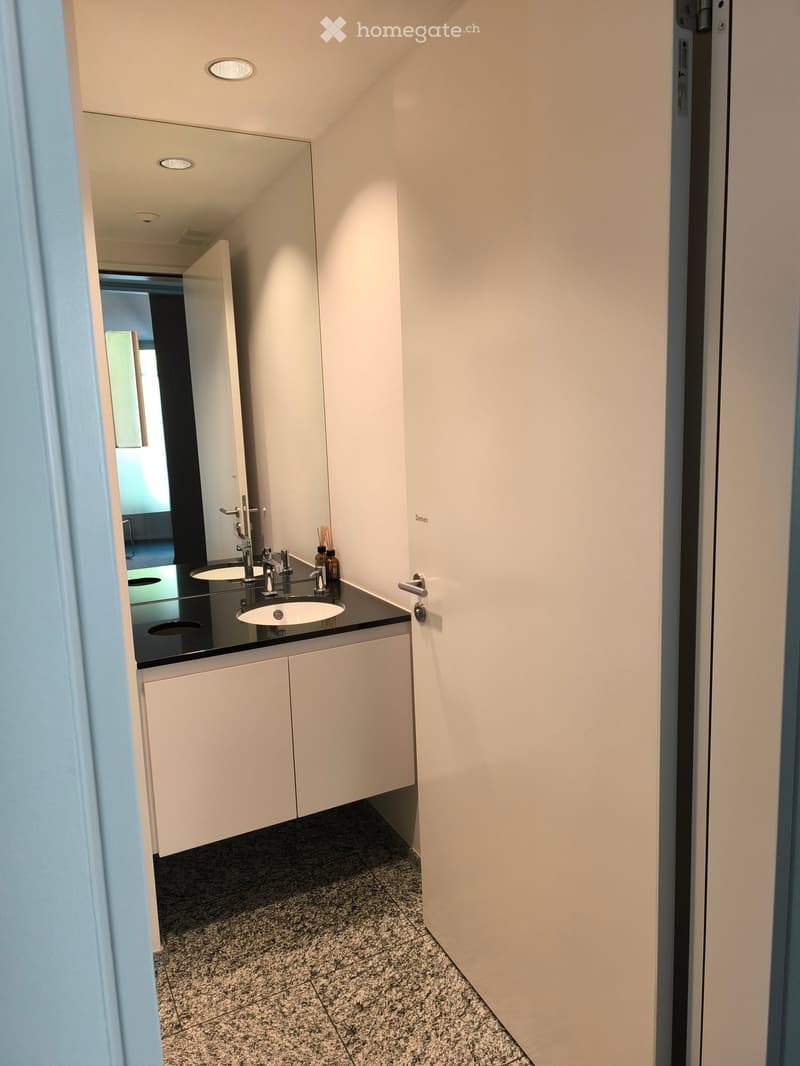 Modern bathroom with white cabinets, black countertop, and two sinks.