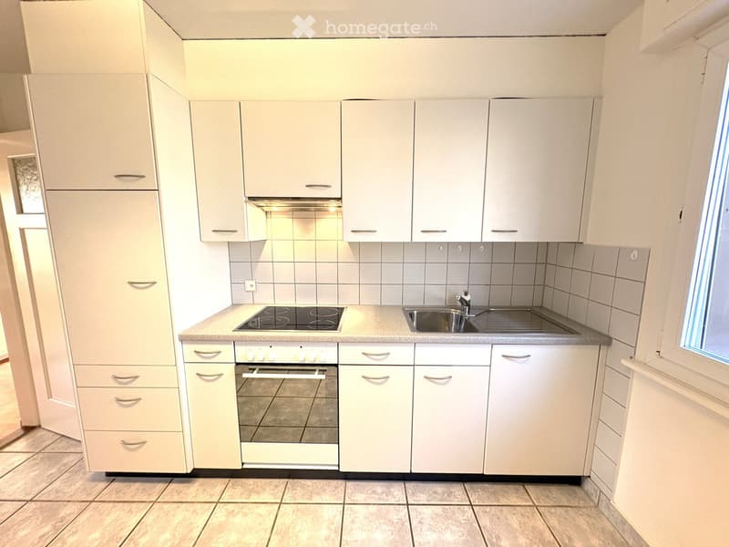 Modern kitchen with white cabinets, stainless steel appliances, and a tiled backsplash.