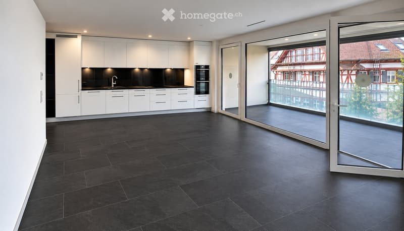 Modern kitchen with white cabinets, black countertops, and a large sliding glass door leading to a balcony with a view of the city.