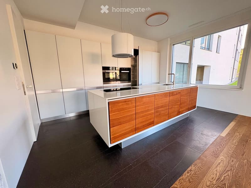 Modern kitchen with white cabinets, wooden accents, stainless steel appliances, and a central island with a countertop.