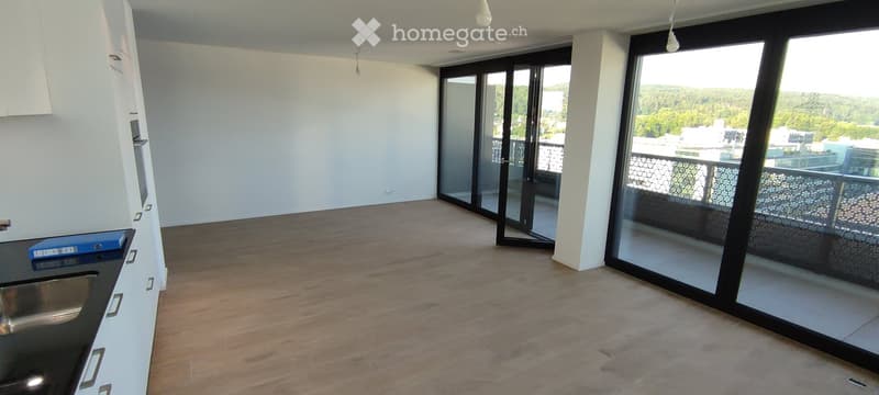 Empty room with wooden flooring, white walls, large sliding glass doors leading to a balcony with a scenic view.