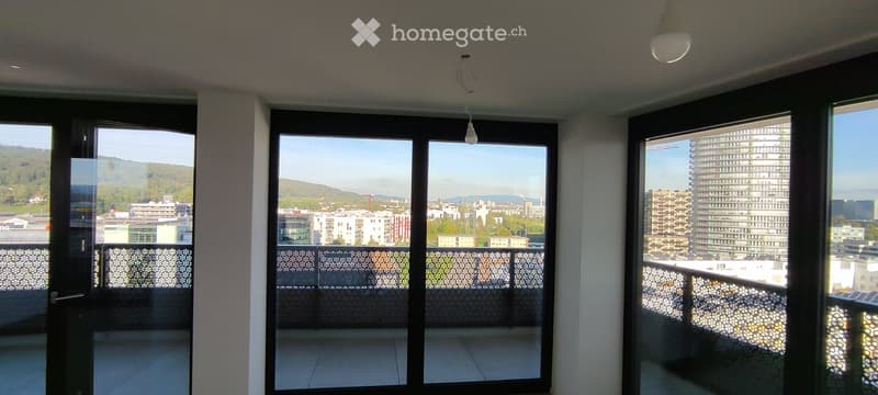 Modern balcony with large glass doors, cityscape view, and decorative railing.