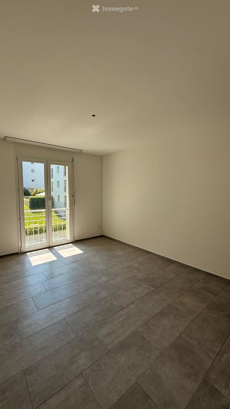 Empty room with tiled floor, white walls, and a sliding glass door leading to a balcony.
