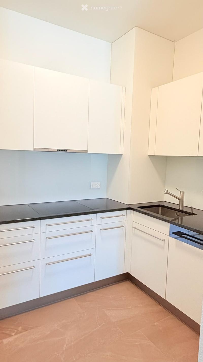 Modern kitchen with white cabinets, stainless steel handles, a sink with a modern faucet, and a black countertop.