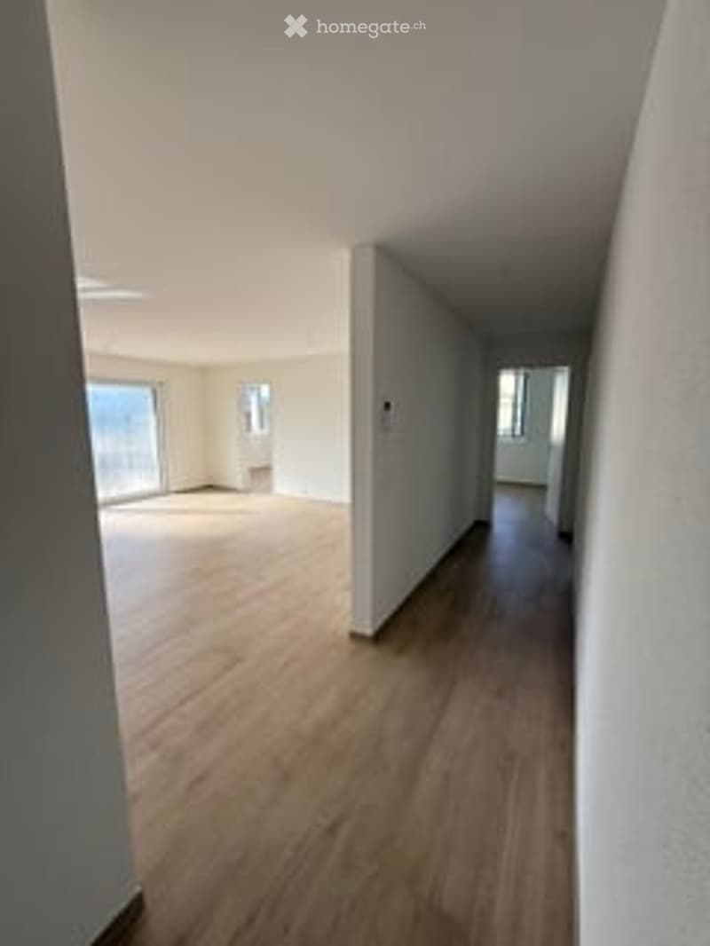 Empty room with light wooden flooring, white walls, and large windows allowing natural light. No furniture or equipment present.