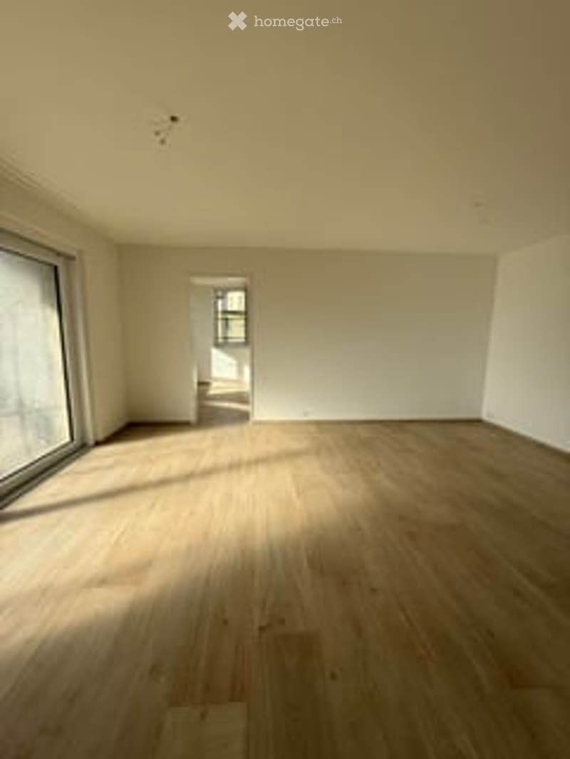 Empty room with wooden flooring, large windows, and white walls. No furniture or equipment present.