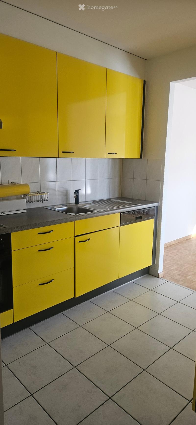 Bright yellow kitchen with modern cabinets, stainless steel sink, and dishwasher.